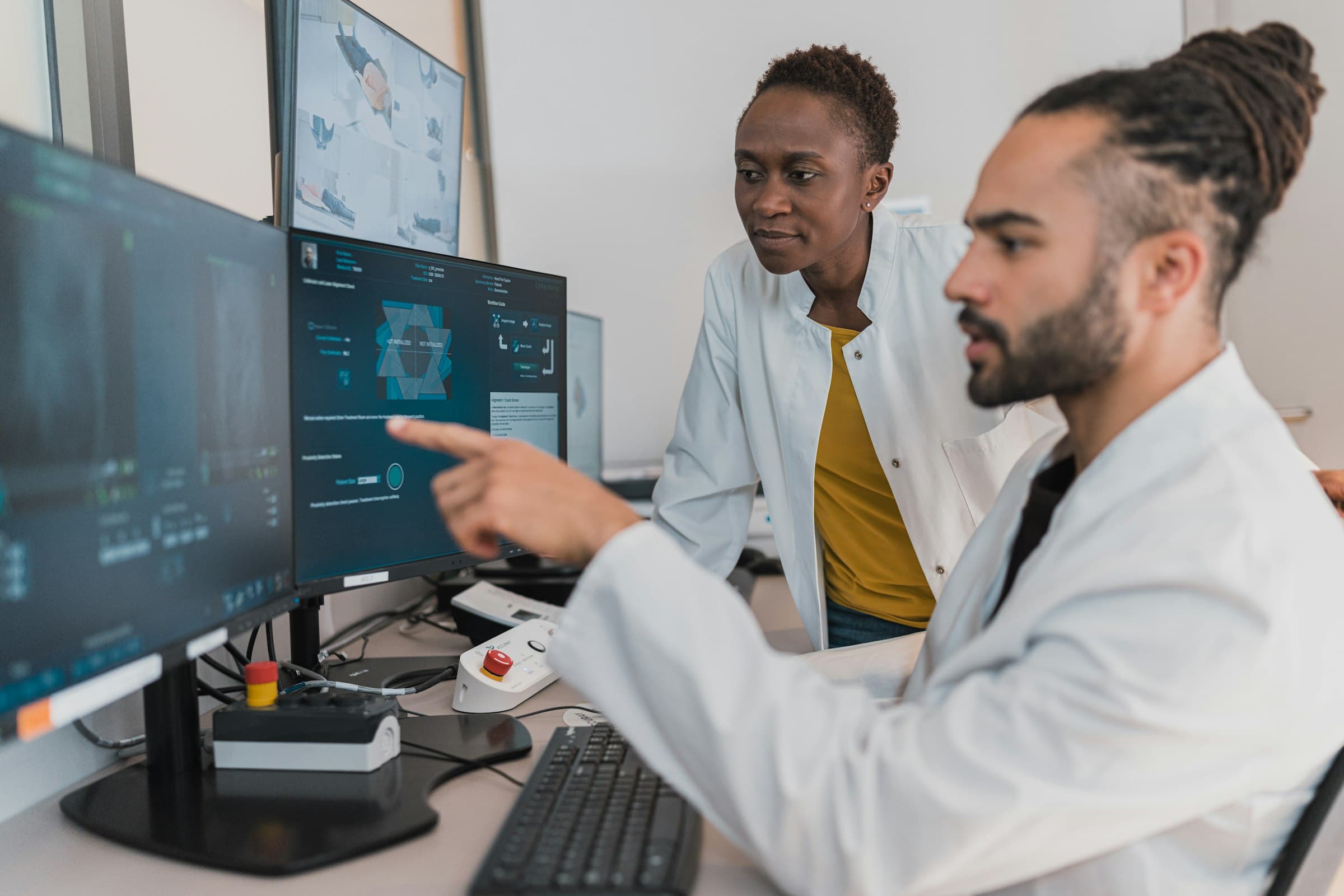 Two clinicians reviewing medical imaging on monitors